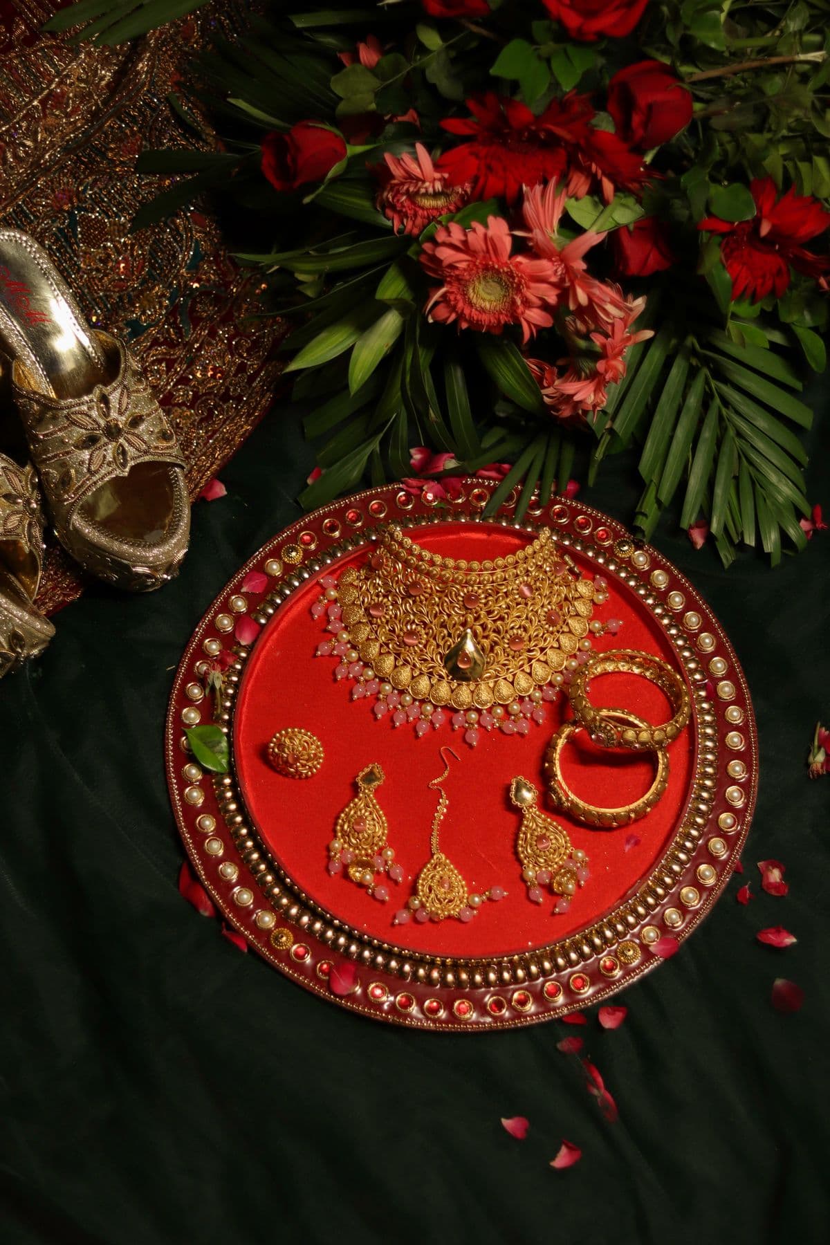 Traditional gold jewelry arranged with red flowers