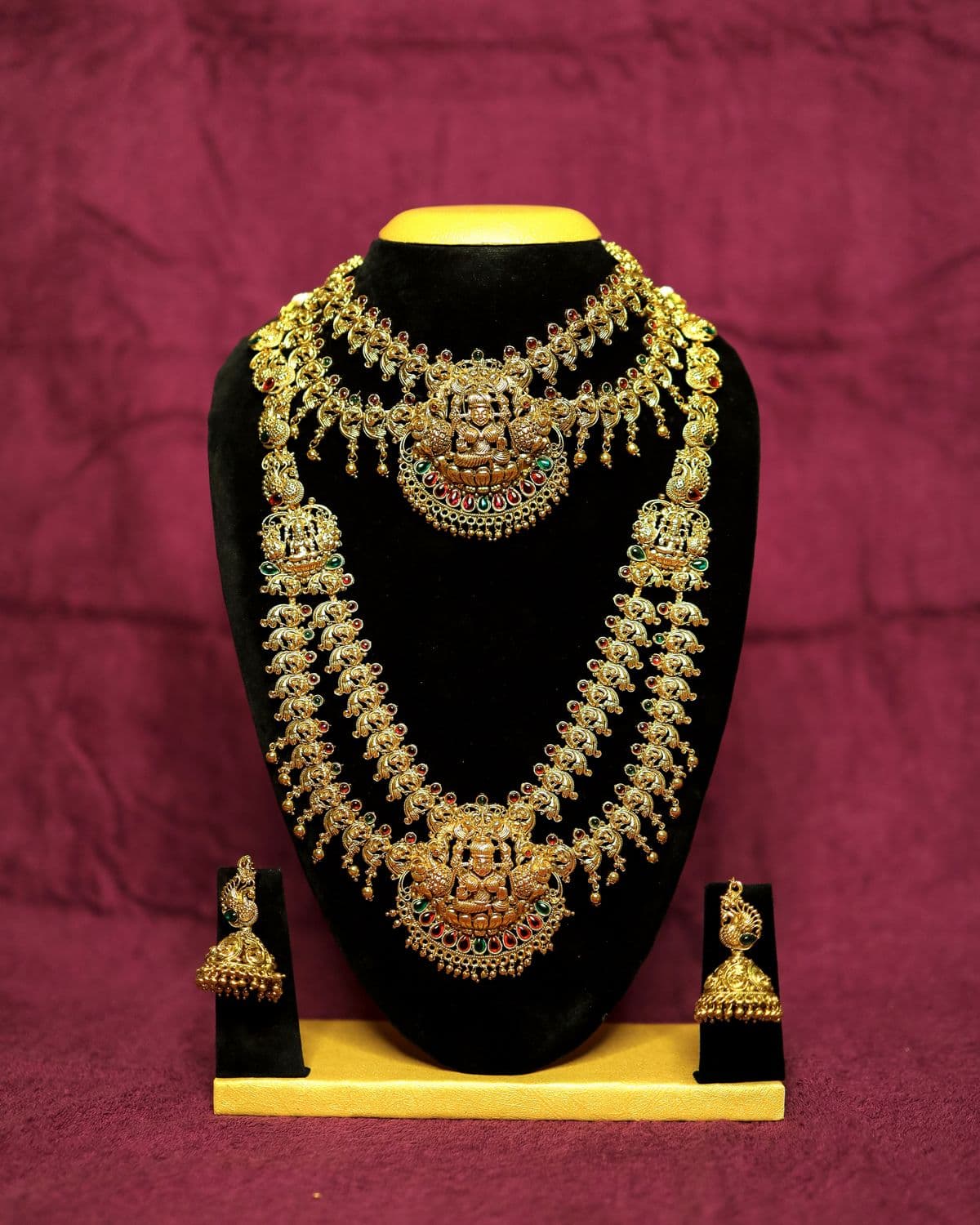 Temple gold necklaces and earrings on a black display